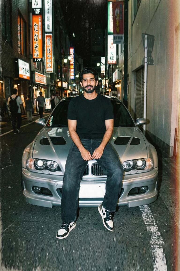 A BMW car guy sitting on the hood of a silver E46 M3 in a neon-lit Japanese alleyway at night, capturing a professional cinematic street photography style.